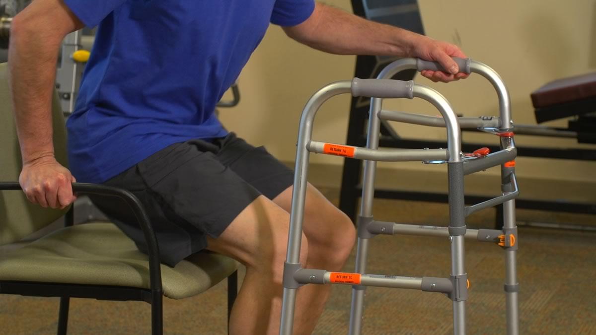 Image of person using walker to stand up from a seated position. 