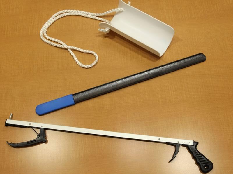 A reacher: a straight rod with a grabbing device on one end, and a handle you squeeze to operate at the other end.  A sock aid: a curved piece of plastic with a rope tied to each side.  